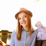 A cheerful woman enjoying a sunny day outside, sitting on a bench with a book in hand.